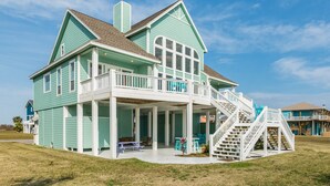 A two-story house with a covered porch and a staircase leading to a balcony.