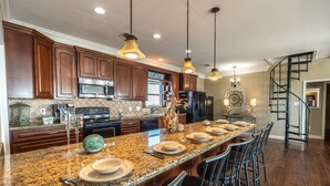 A kitchen with granite countertops, wooden cabinets, and a central island with bar stools.