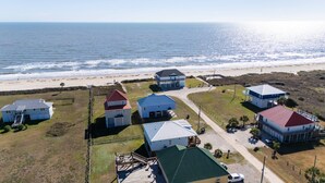 An aerial view of a coastal property with multiple buildings, a beach, and the ocean.