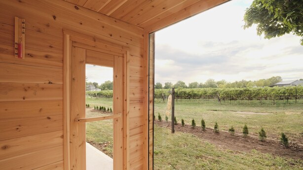 A wooden cabin with a large window offering a view of a vineyard. - Retreat by the Vineyard |Panoramic Sauna |Hot Tub |EV Charger (Niagara-on-the-Lake)