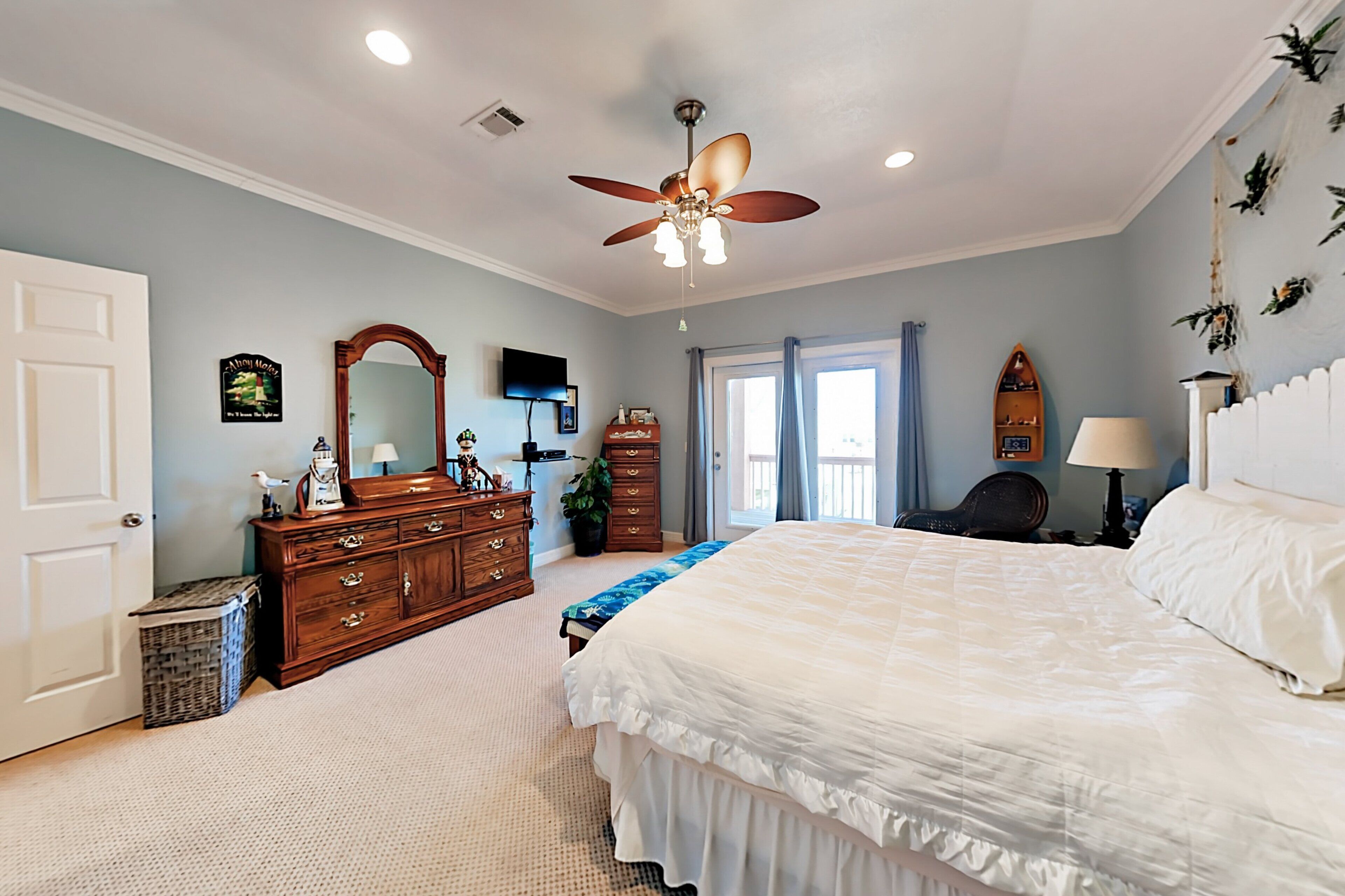 A bedroom with a bed, dresser, ceiling fan, and a window with curtains.