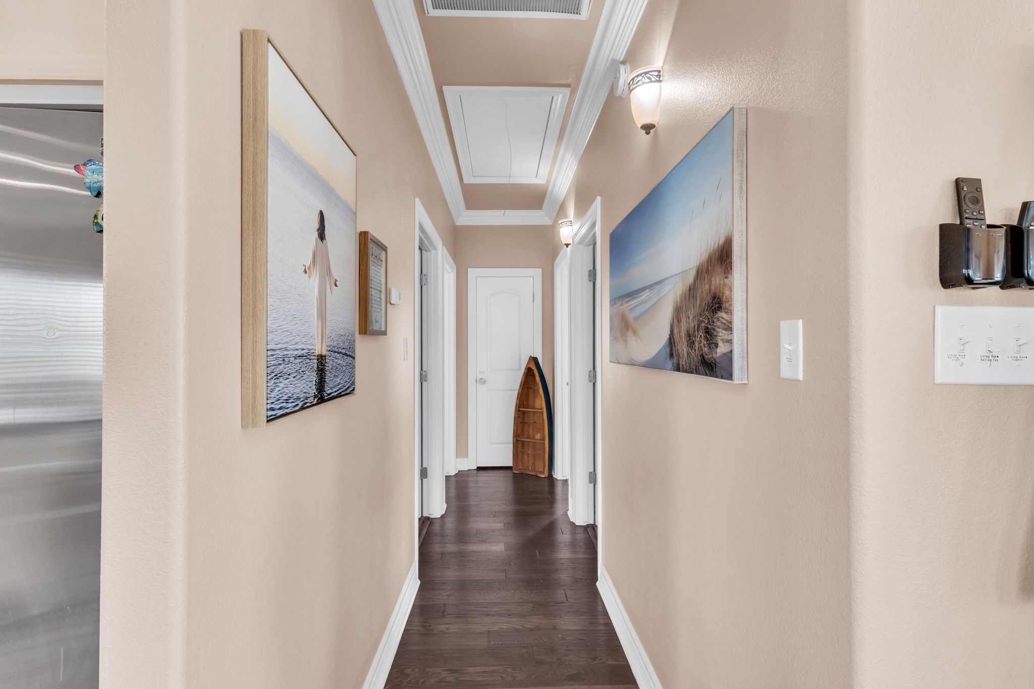 Un couloir doté d’un plancher en bois, de murs de couleur beige et d’œuvres d’art encadrées.