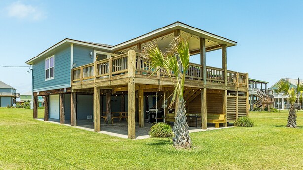 A two-story house with a covered porch, a garage, and a small patio area. - Dream | Steps to the Beach | Large Deck (Crystal Beach)