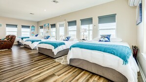 A hotel room with two beds, a wooden floor, and large windows.
