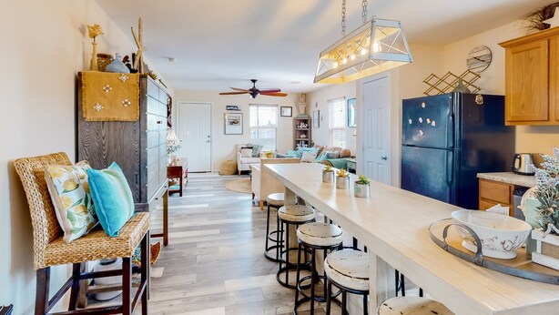 Una cocina con una isla grande, taburetes de bar, armarios de madera y un refrigerador negro.