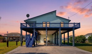 A two-story house with a covered porch, a staircase, and a satellite dish. - Escape | Gulf Views | Large Deck | Pet Friendly (Crystal Beach)