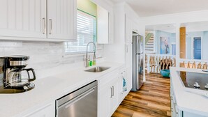 A modern kitchen with white cabinetry, a stainless steel refrigerator, and a coffee maker. - Dream | Canal Front | Firepit | Kayking & Fishing (Surfside Beach)