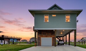 A two-story house with a garage, a covered porch, and a view of the sunset.