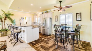 A spacious kitchen with a central island, modern appliances, and a dining area with bar stools. - Perfect | Steps to Beach | Firepit | Sleeps 10 (Crystal Beach)