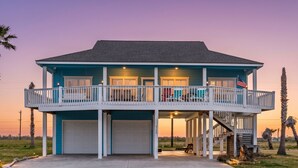 A two-story house with a balcony, garage doors, and an American flag. - Perfect | Steps to Beach | Firepit | Sleeps 10 (Crystal Beach)
