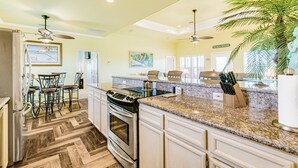A kitchen with granite countertops, stainless steel appliances, and a herringbone wood floor. - Perfect | Steps to Beach | Firepit | Sleeps 10 (Crystal Beach)
