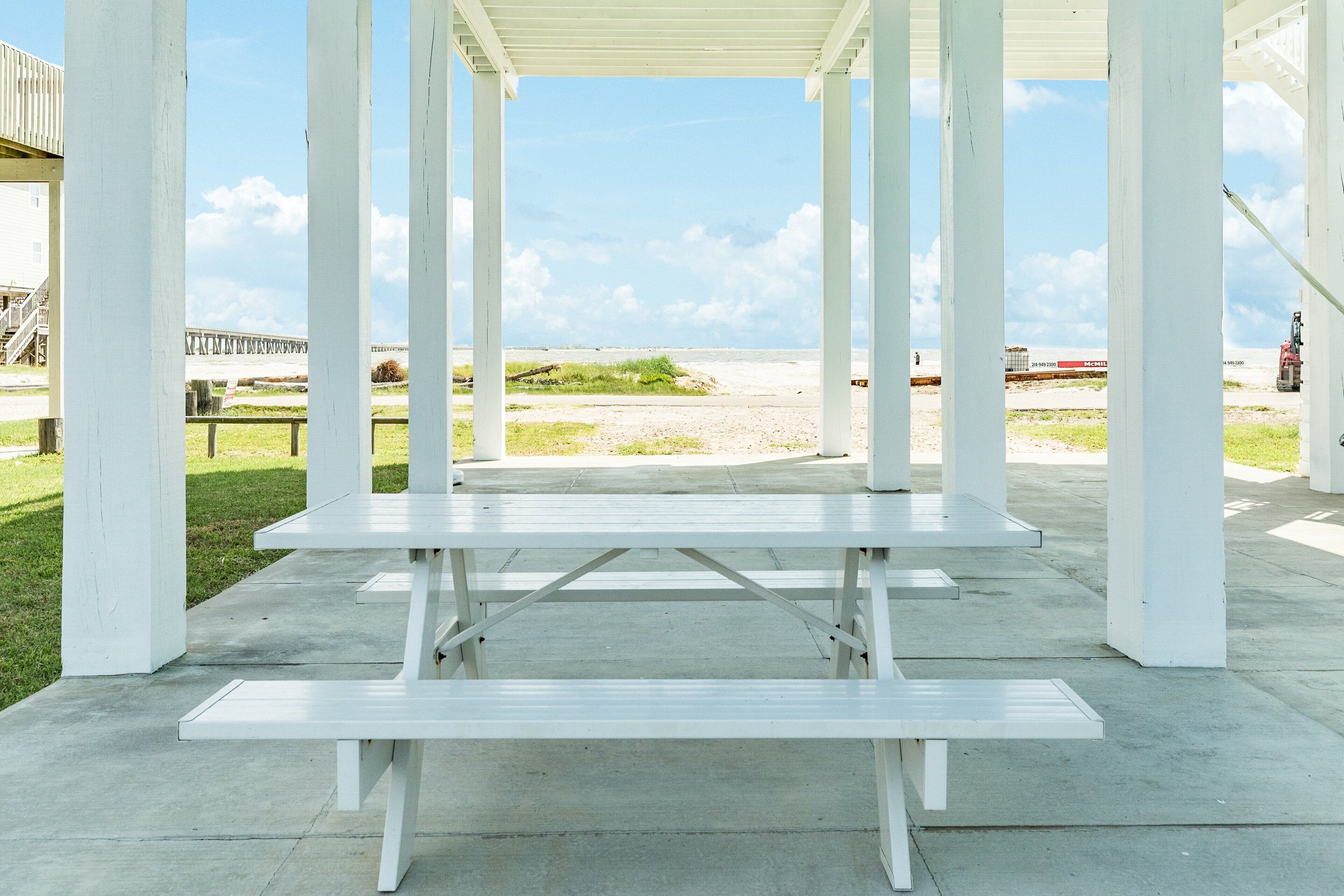 A white pavilion with a concrete floor and benches.