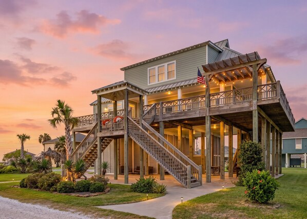 A two-story house with a covered porch, a staircase, and a flag.