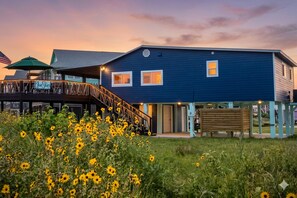 A two-story building with a blue exterior, a wooden deck with a railing, and a sign that reads 'Blue Skies.' - Haven | Ocean View | Large Deck | Pet Friendly (Surfside Beach)