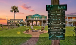 A resort with a fire pit area, outdoor seating, and a sign listing amenities like adult supervision and no gasoline. - Retreat | Steps to Beach | Firepit | Family Fun (Crystal Beach)
