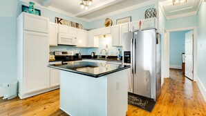 A kitchen with white cabinets, a black countertop, and a stainless steel refrigerator. - Perfect | Gulf Views | Furnitured Deck | Sleeps 10 (Gilchrist)
