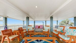 A covered outdoor seating area with wooden furniture and a view of the beach. - Perfect | Gulf Views | Furnitured Deck | Sleeps 10 (Gilchrist)
