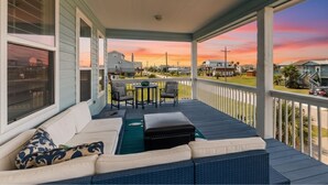 A covered porch with a sofa, chairs, and a table.