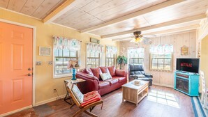 A cozy living room with a red leather sofa, a wooden rocking chair, and a television. - Prime | Beachfront | Beach Access | Sleeps 8 (Surfside Beach)