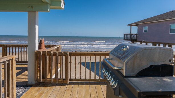 A wooden deck with a grill and a view of the ocean. - Prime | Beachfront | Beach Access | Sleeps 8 (Surfside Beach)