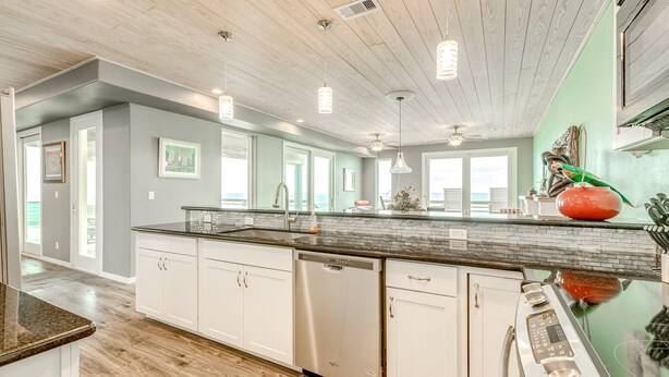 A modern kitchen with white cabinets, a stainless steel dishwasher, and a large island with a sink. - Beachfront 4br, Hot Tub, Multiple Deck, Sleeps 16 (Gilchrist)