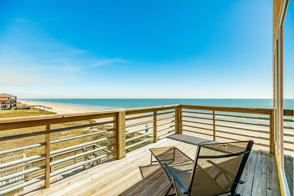 A wooden deck with a view of the beach and ocean.