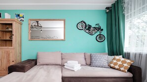 A room with a sofa, a wooden cabinet, and a wall-mounted motorcycle decoration. - Wild and Free Urban Jungle Apartment (Łódź)