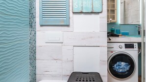A laundry area with a washing machine, a drying rack, and a laundry basket. - Wild and Free Urban Jungle Apartment (Łódź)