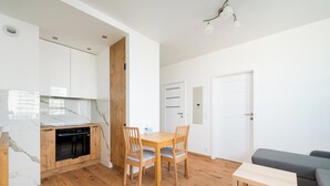 Una cocina compacta con armarios de madera, horno integrado y una mesa de comedor con sillas.
