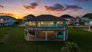 A two-story house with a balcony, a covered porch, and a lawn.