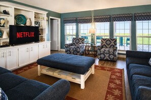 A living room with a television, a sofa, a loveseat, and a patterned armchair.