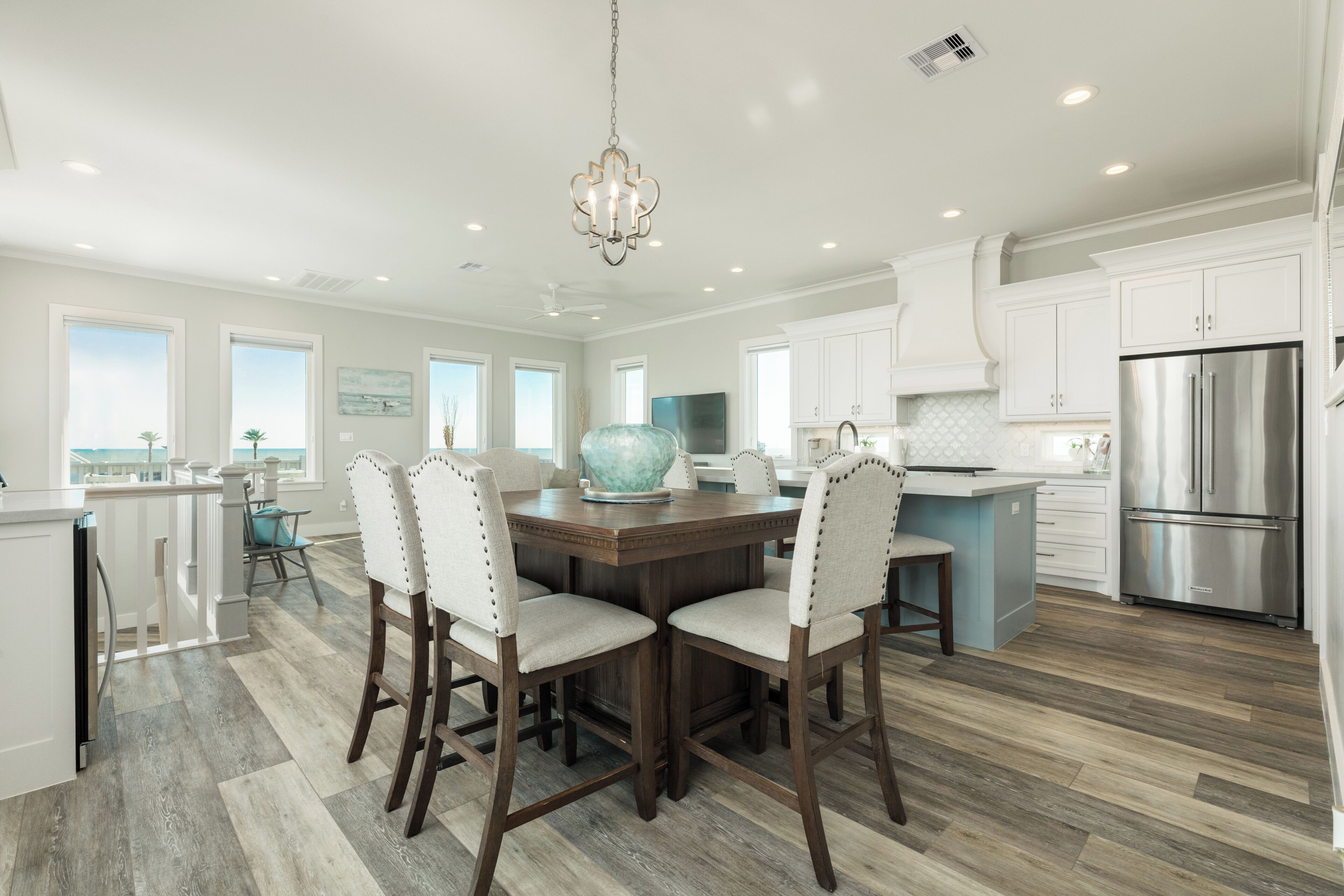 A modern kitchen with a central island, white cabinetry, and a stainless steel refrigerator.