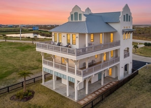 A multi-story house with a balcony, a porch, and a view of the surrounding landscape.