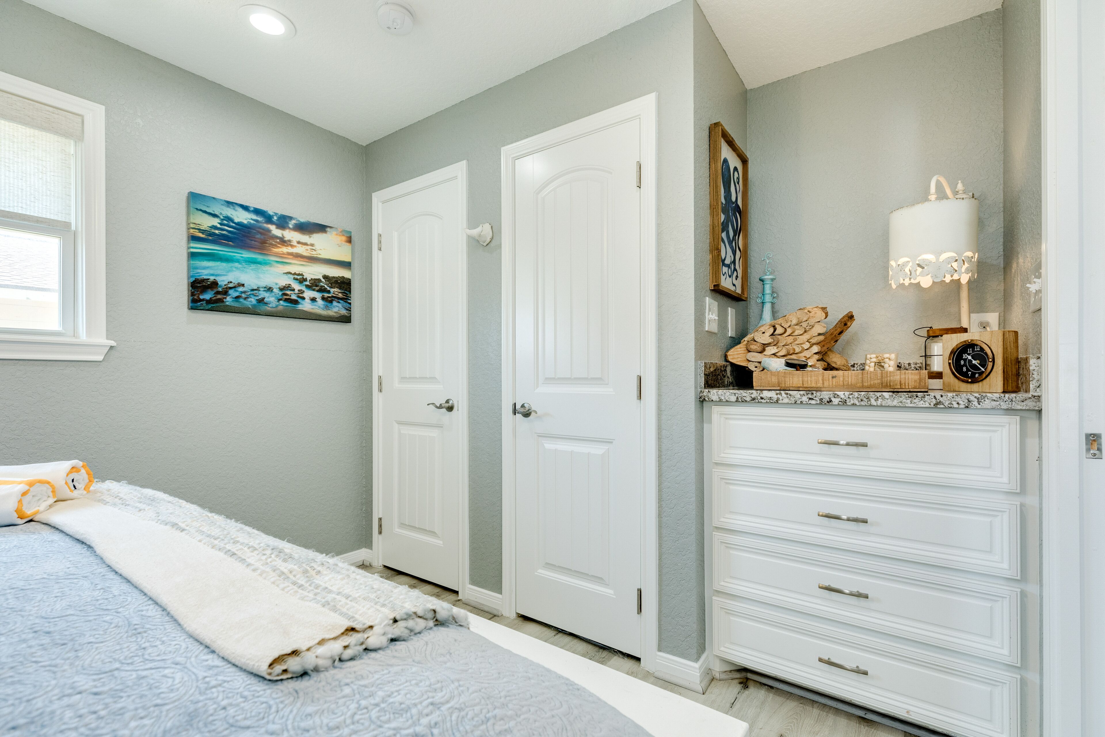 Un dormitorio con cama, cómoda, mesita de noche y un cuadro en la pared.
