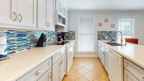 Una cocina moderna con gabinetes blancos, un salpicadero de azulejos y una isla central con un lavamanos.