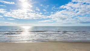 A beach with a clear sky and sunlight reflecting on the water.