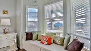A room with a built-in bench by the windows, a lamp, and decorative pillows.