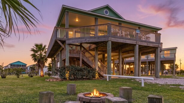 A large two-story house with a balcony, a fire pit, and a well-maintained lawn.