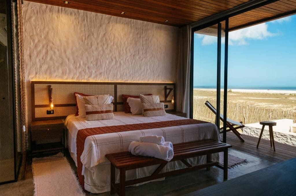 Ein Schlafzimmer mit einem großen Bett, einer Bank und Blick auf den Strand.