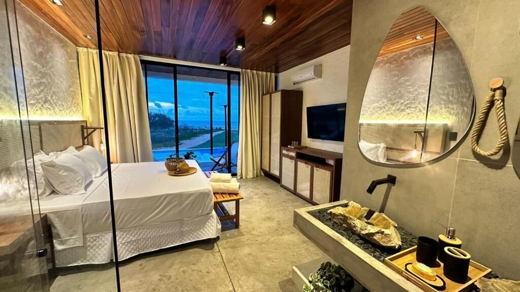 A modern hotel room with a bed, a TV, a large mirror, and a view of the outdoors.