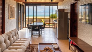 A living room with a sofa, a dining table with chairs, a TV, and a kitchen area with a refrigerator.