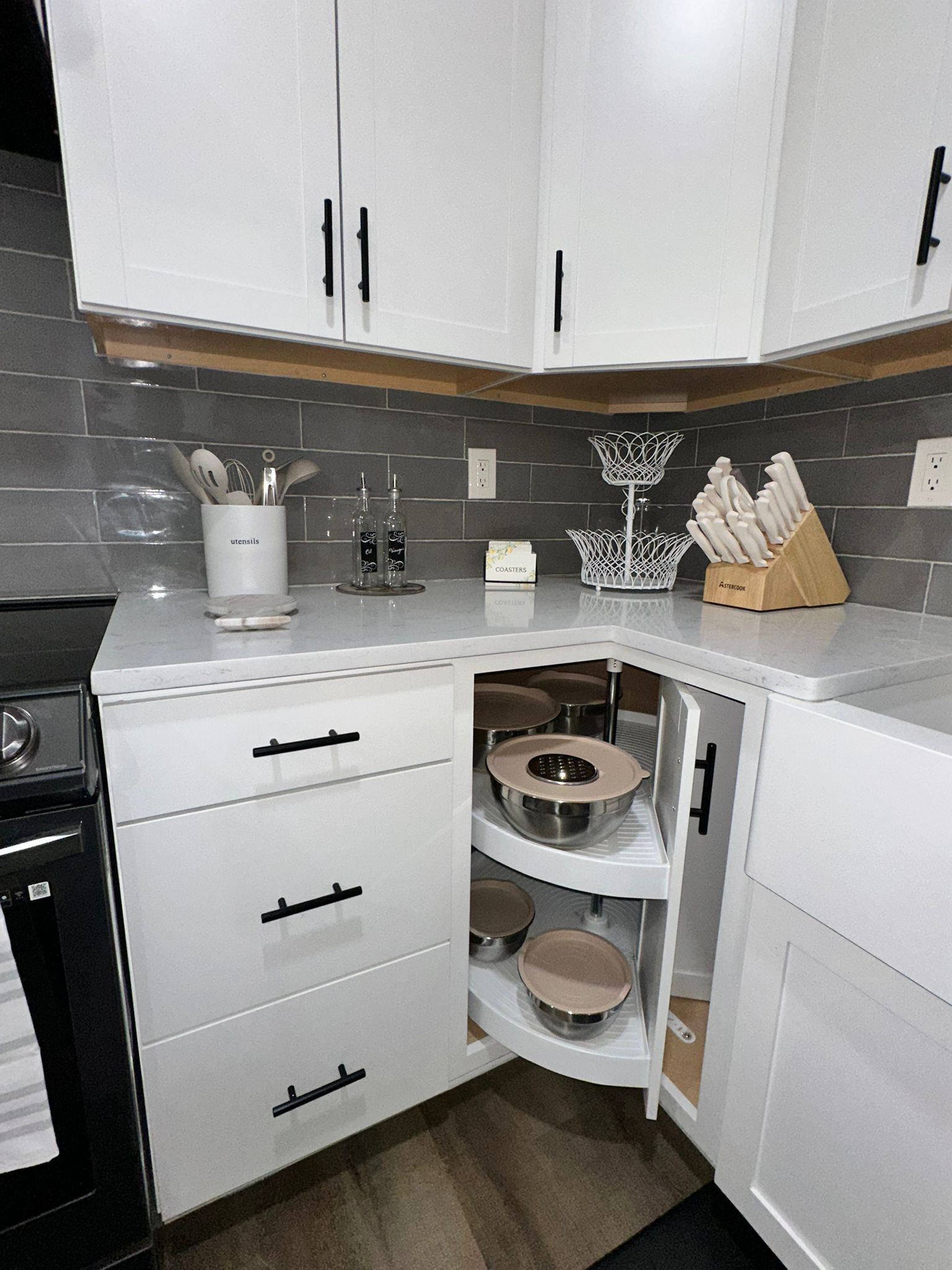 A modern kitchen with white cabinets, a built-in oven, and a countertop with kitchen utensils and appliances.