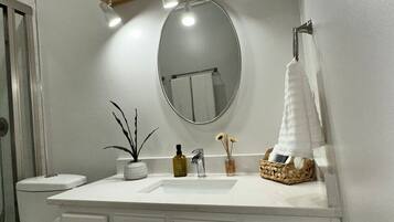 A bathroom with a white vanity, a round mirror, and a towel rack.