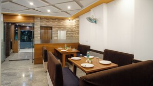 A modern conference room with a wooden table, brown upholstered chairs, and a glass partition.