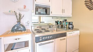 A compact kitchen with white cabinets, a microwave, a stove, and a dishwasher.