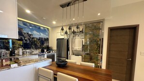 Une cuisine moderne dotée d’un îlot central en bois, d’appareils électroménagers en acier inoxydable et de luminaires suspendus.