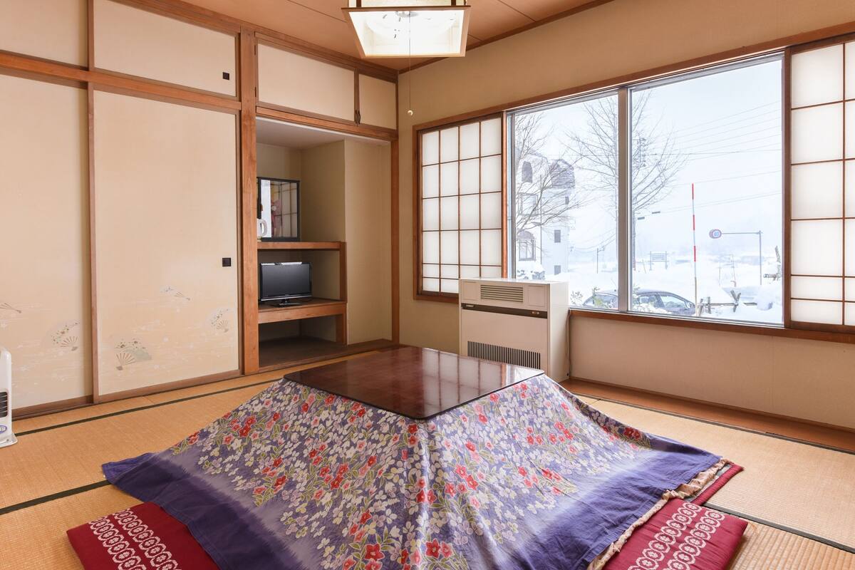 A traditional Japanese room with tatami flooring, a low table, and sliding doors.