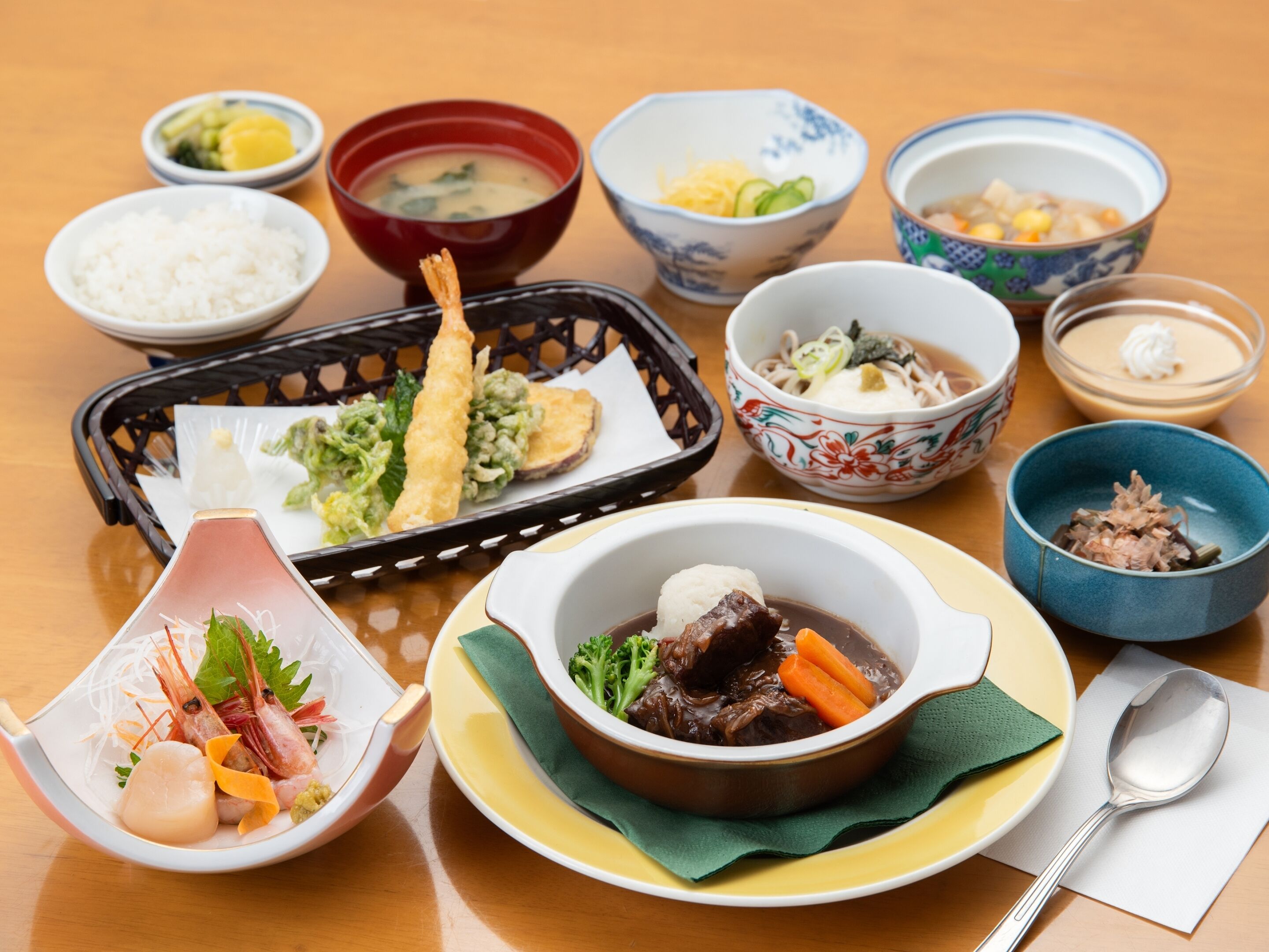 A variety of dishes including seafood, vegetables, and soup, arranged on a wooden table.