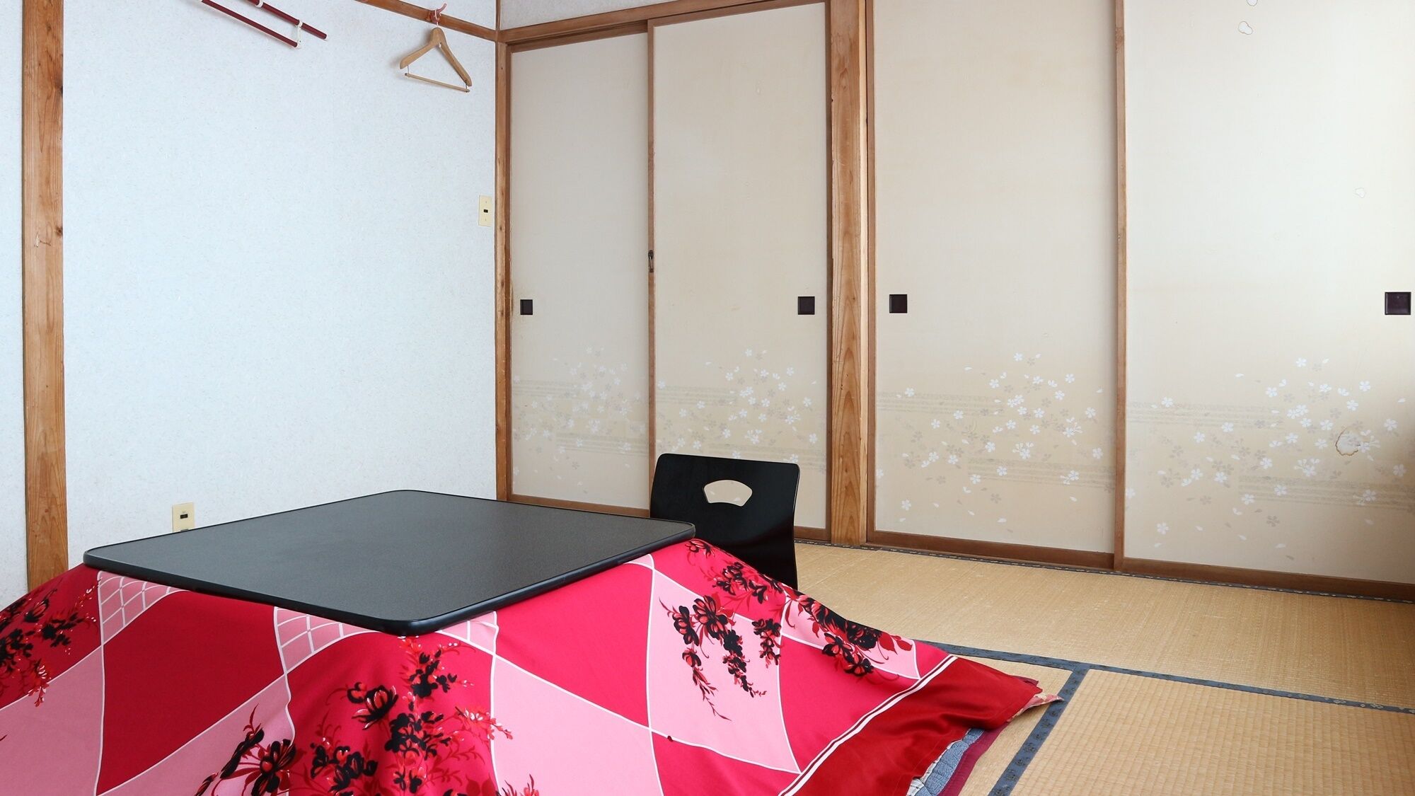Une pièce dotée d’un sol recouvert de tatamis, d’une table noire et d’une porte coulissante traditionnelle japonaise.
