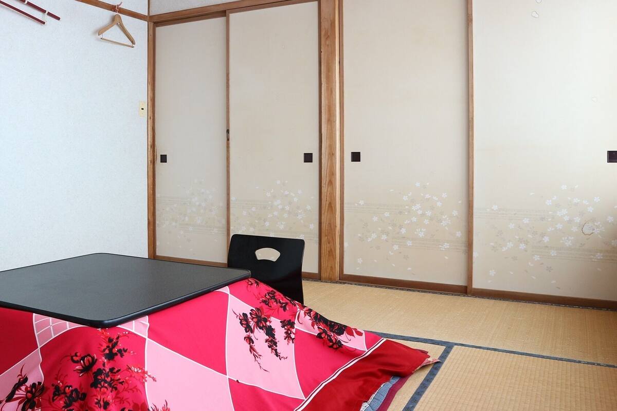A room with a tatami mat floor, a black table, and a traditional Japanese sliding door.